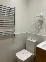 Interior Apartment bathroom with toilet, chrome heated towel rail and wall-mounted hairdryer